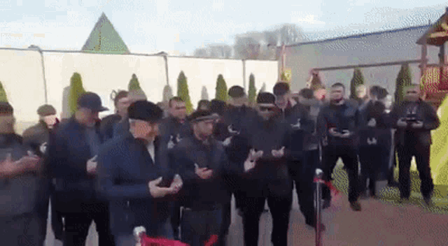 a group of men are standing in front of a pyramid while holding their phones