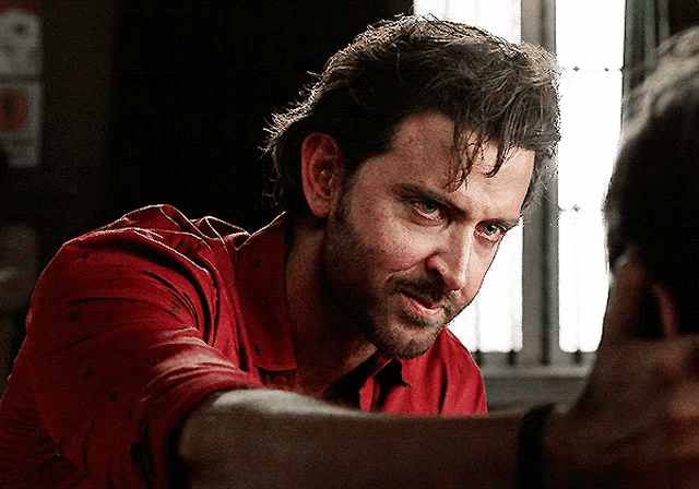 a man in a red shirt looks down at something