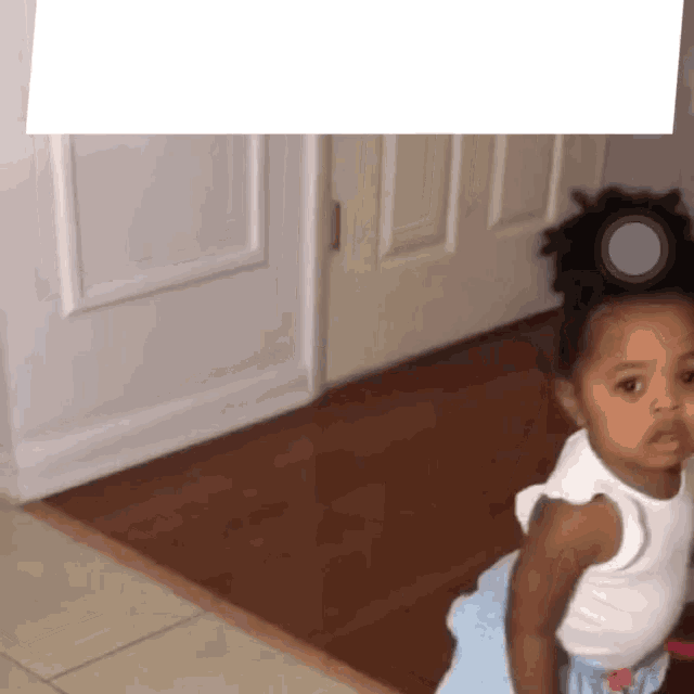 a little girl in a white tank top and blue skirt
