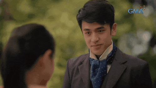 a man in a suit and tie is looking at a woman with the gma logo in the background
