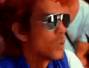 a man wearing sunglasses has the letter t on his lens