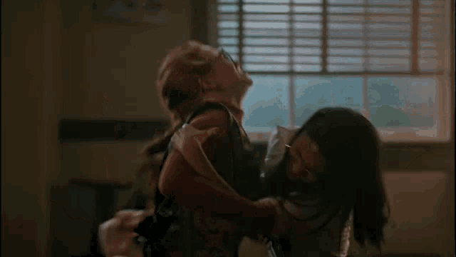 a man and a woman are dancing in a room with a window in the background .