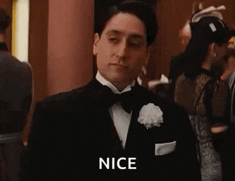 a man in a tuxedo and white gloves is giving a thumbs up .