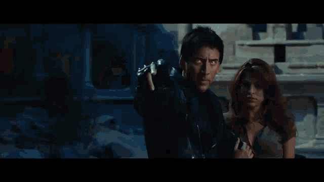 a man in a black jacket is holding a fireball in his hand in a dark room .