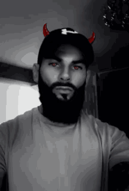 a man with a beard is wearing a hat with devil horns