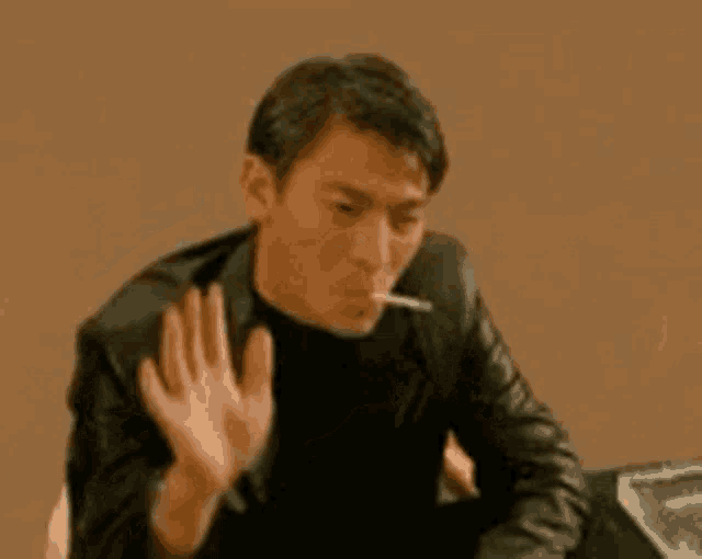 a man is smoking a cigarette while giving a thumbs up .