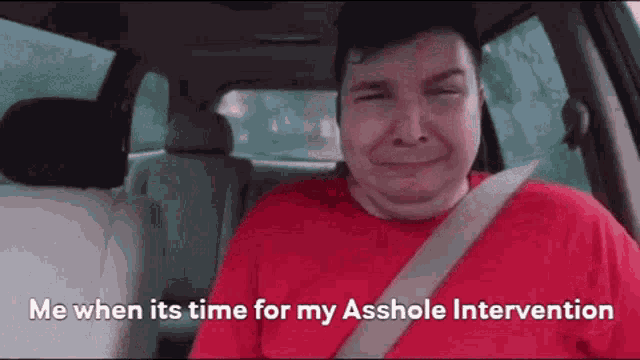 a man in a red shirt is sitting in the back seat of a car with his eyes closed .