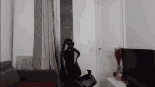 a black gaming chair in a living room with a tv in the background