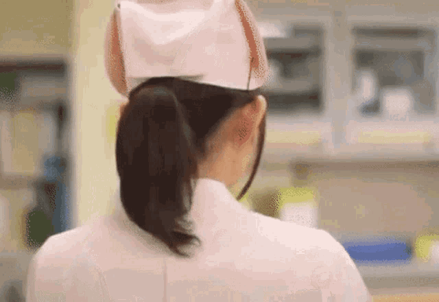 the back of a nurse wearing a ponytail and a hat