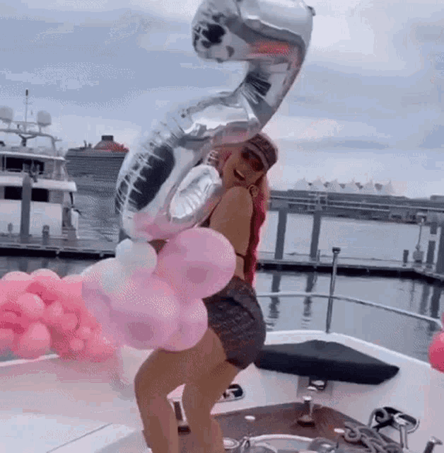 a woman is standing on a boat holding balloons .