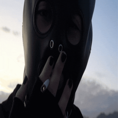 a person wearing a gas mask covering their face with their hands
