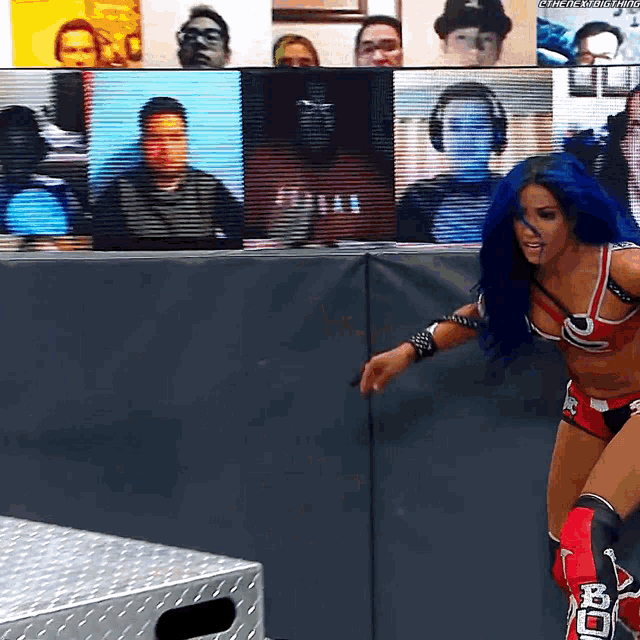 a female wrestler with blue hair and knee pads that say bc