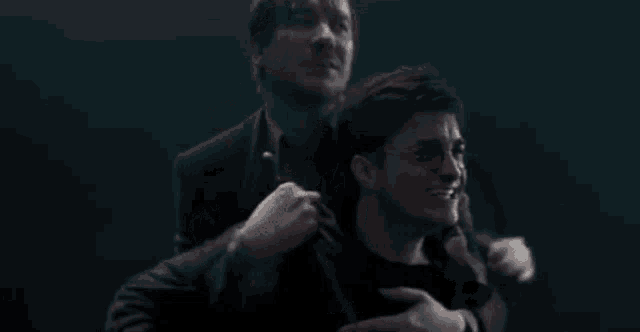 harry potter is sitting on the back of a man in a dark room giving a thumbs up .