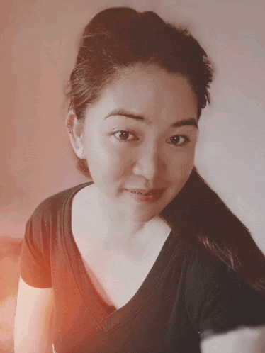 a woman wearing a black shirt with a ponytail is smiling