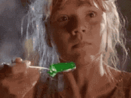 a woman is eating a green candy with a spoon .