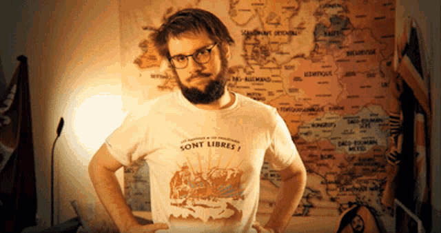a man wearing a t-shirt that says sont libres stands in front of a map