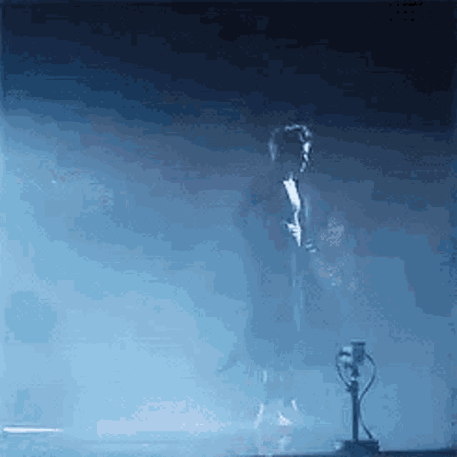 a man is standing in front of a microphone on a stage in a dark room .