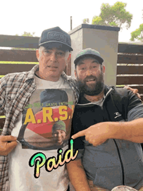 two men are posing for a picture and one has a shirt that says a.r.s. on it