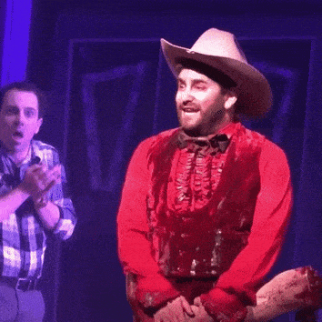 a man in a red shirt and cowboy hat is on stage