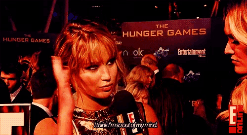 a woman is talking into a microphone in front of a sign that says the hunger games