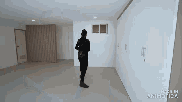 a woman is walking through an empty room with the words made in animatica on the bottom right