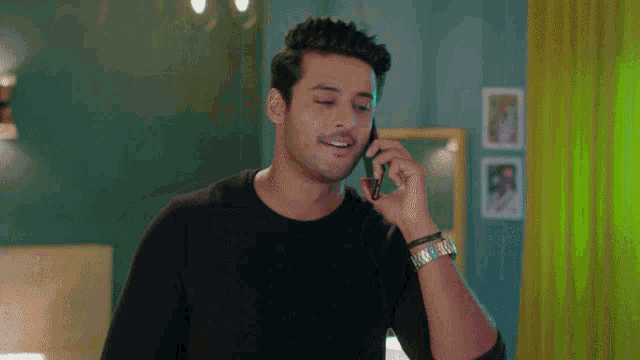 a man talking on a cell phone with a watch on his wrist