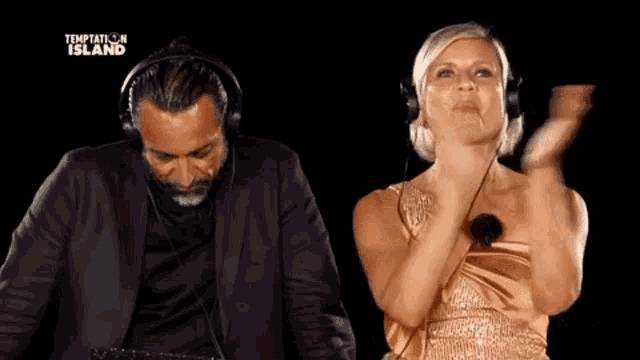 a man in a suit and a woman in a dress are dancing in front of a screen that says temptation island