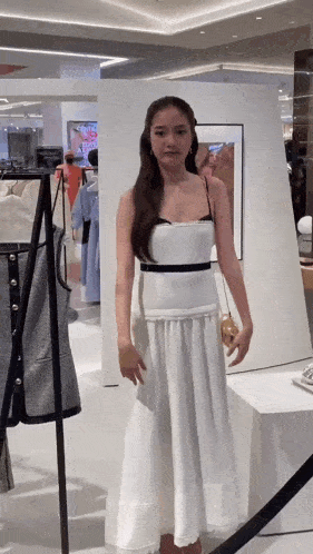 a woman in a white dress is standing in front of a mirror .