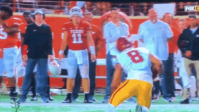 a football player with the number 8 on his jersey stands on the field
