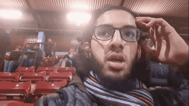a man wearing glasses and a scarf is taking a selfie