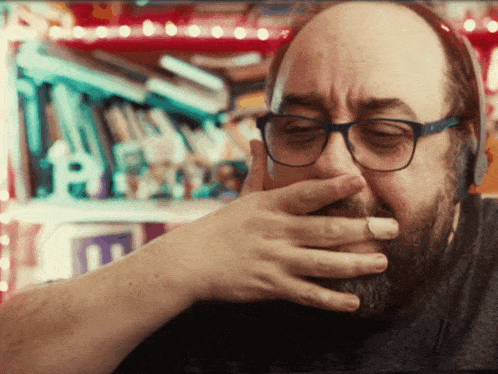 a man with glasses covering his mouth with his hand