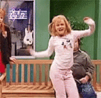 a woman in a white shirt is dancing in front of a guitar poster .
