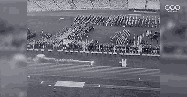 a black and white photo of a stadium with the olympics logo on the bottom
