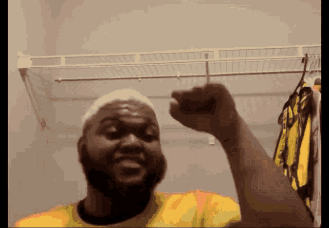 a man in a yellow shirt is raising his fist
