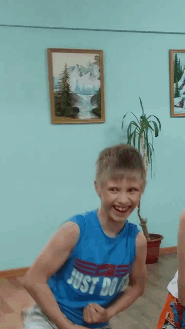 a boy wearing a blue shirt that says just do it smiles