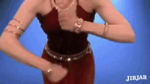 a woman in a red dress is dancing with her hands on her chest .