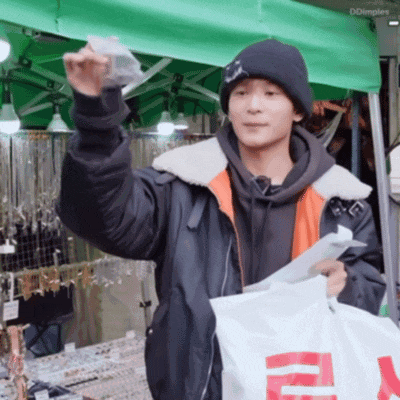 a man wearing a black beanie is holding a white bag with a red r on it ..