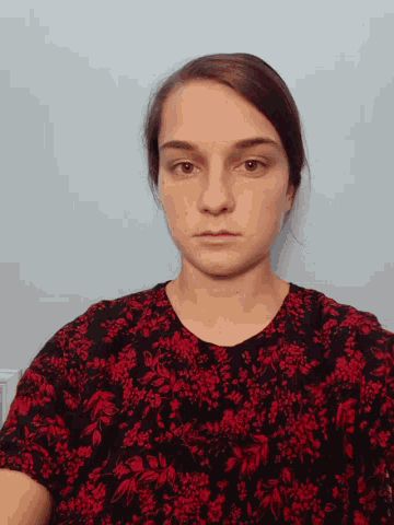 a woman in a red and black floral shirt is looking at the camera