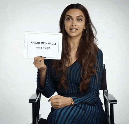 a woman sitting in a chair holds up a sign that says kabab mein haddi