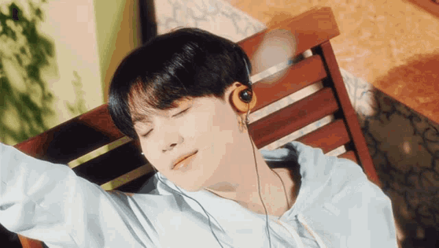 a man wearing headphones is laying on a wooden chair