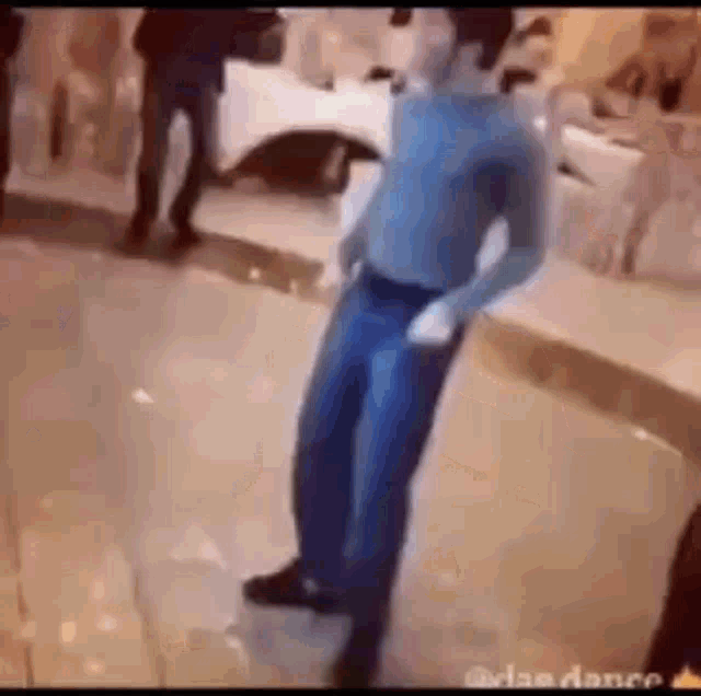 a man in a blue shirt and blue jeans is dancing on a dance floor .