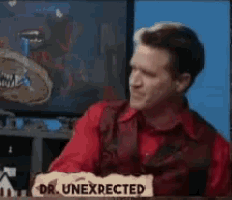 a man in a red shirt is sitting in front of a sign that says dr unexpected