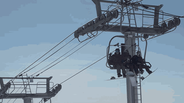 a group of people are riding a ski lift with a snowboarder on it
