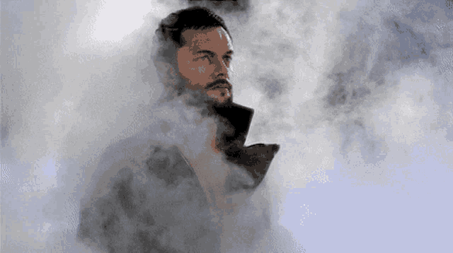 a man with a beard is standing in a cloud of smoke