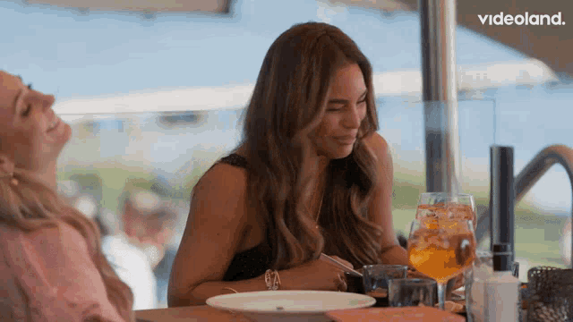 two women are sitting at a table with a videoland logo in the background