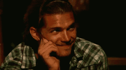 a man in a plaid shirt is sitting down with his hand on his chin .