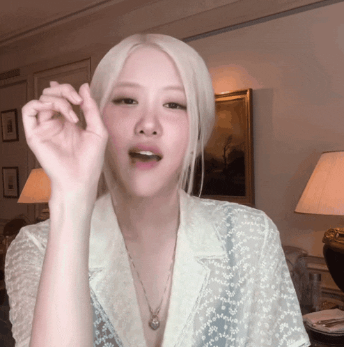 a woman with blonde hair is wearing a necklace and a white shirt