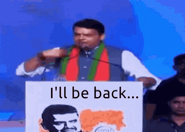 a man stands behind a podium that says i 'll be back