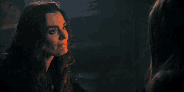 two women are standing next to each other in a dark room and looking at each other .