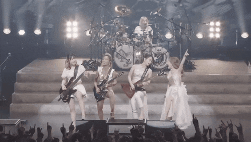 a group of women playing guitars on a stage with a drum set that says king crimson